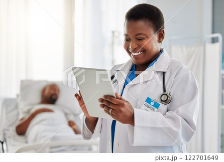 Happy news with doctor reading exciting email or test results on digital tablet, feeling positive at hospital. Young health care worker getting good news of cure or treatment for her sick patient 122701649