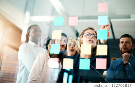 Creative group or business team planning for innovation with sticky notes on glass wall. Coach or leader sharing vision and mission in a meeting. Manager sharing ideas and explaining strategy Creative group or business team planning for innovation with sticky notes on glass wall. Coach or leader sharing vision and mission in a meeting. Manager sharing ideas and explaining strategy 122701817