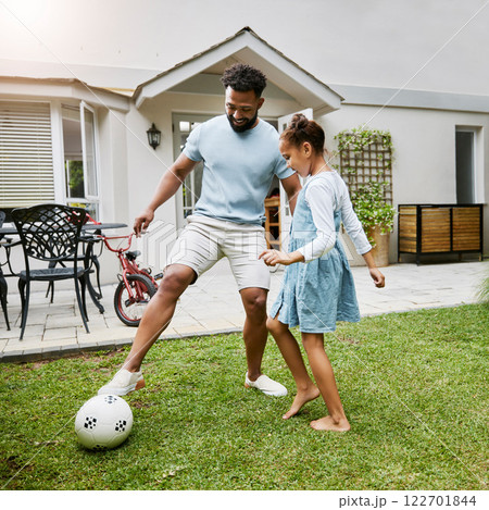 Father and daughter bonding, playing with soccer ball in backyard at home, smiling and having fun. Happy parent being playful and enjoying family time with his child. Guy being active with his kid 122701844