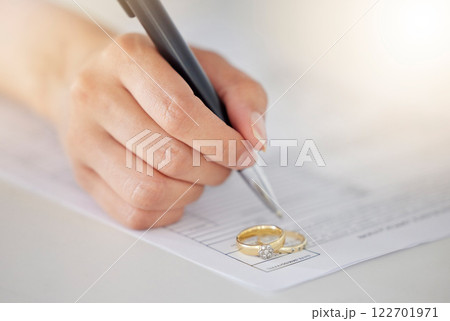 Woman hand signing legal divorce documents, deal or paper contract in a lawyer office with ring placed on table. Person writing signature on marriage paperwork after agreement at family law office Woman hand signing legal divorce documents, deal or paper contract in a lawyer office with ring placed on table. Person writing signature on marriage paperwork after agreement at family law office 122701971