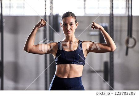 Gym, fitness and woman flexing muscles with energy to show off her biceps and strong abs in a sports studio. Training, exercise and workout motivation of a healthy, body and muscular in a portrait Gym, fitness and woman flexing muscles with energy to show off her biceps and strong abs in a sports studio. Training, exercise and workout motivation of a healthy, body and muscular in a portrait 122702208