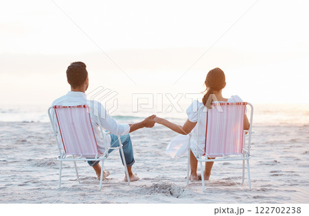 Couple, beach chair and holding hands on vacation, love and outdoor at sunset, back and bonding in summer. People, man and woman with mock up space, relax and view on holiday by ocean in Indonesia 122702238
