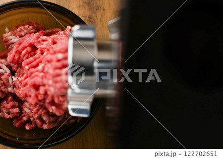 The concept of healthy and proper nutrition, cooking. Top and left view of red ground beef with streaks of fat coming out of a metal grinder with space for text on the right on a black background 122702651