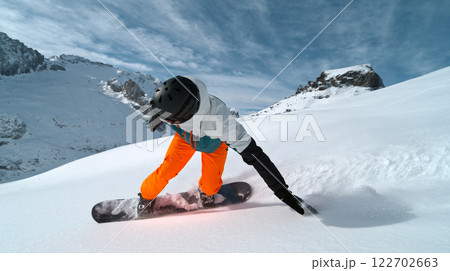 Snowboard rider riding down fresh powder during sunny day , Alpine scenery Snowboard rider riding down fresh powder during sunny day , Alpine scenery 122702663