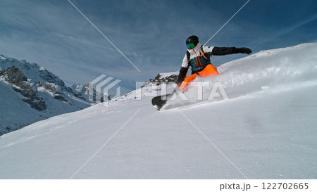 Snowboard rider riding down fresh powder during sunny day , Alpine scenery 122702665