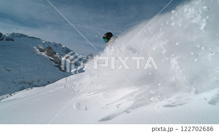 Snowboard rider riding down fresh powder during sunny day , Alpine scenery Snowboard rider riding down fresh powder during sunny day , Alpine scenery 122702686