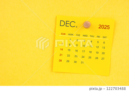 December 2025 calendar sheet with thumbtack on yellow background. 122703488