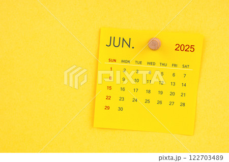 June 2025 calendar sheet with thumbtack on yellow background. 122703489