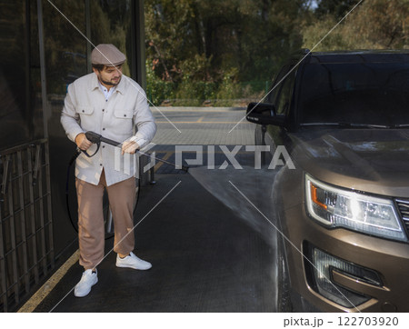 man washing a car in a self-service car wash station with wahing foam. Wash car self-service station man washing a car in a self-service car wash station with wahing foam. Wash car self-service station 122703920