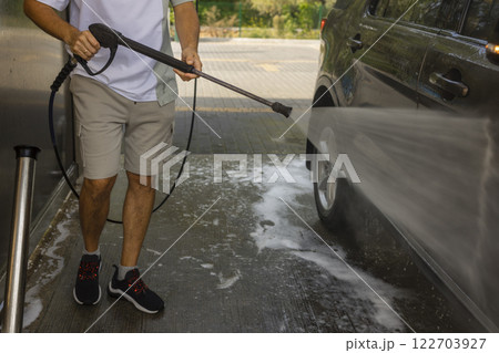 man washing a car in a self-service car wash station with wahing foam. Wash car self-service station 122703927