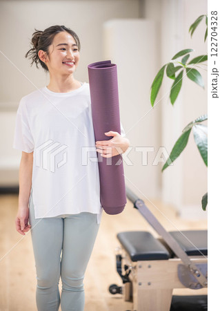 ヨガマットを持って笑う若い女性 122704328