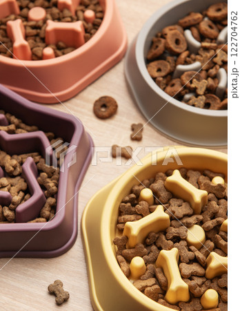 Different shapes of slow feeder bowls with dry food for dogs on wooden surface Different shapes of slow feeder bowls with dry food for dogs on wooden surface 122704762