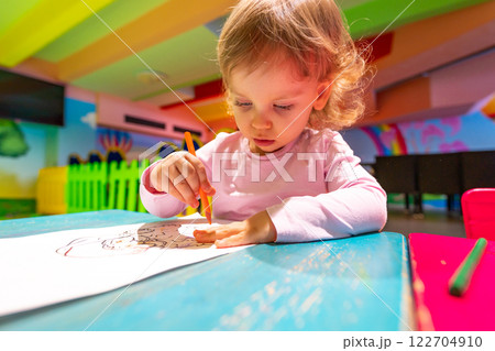 A curious child developing artistic skills in a vibrant and playful environment. 122704910