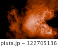 Large orange cloud of smoke is billowing out of a black background. 122705136