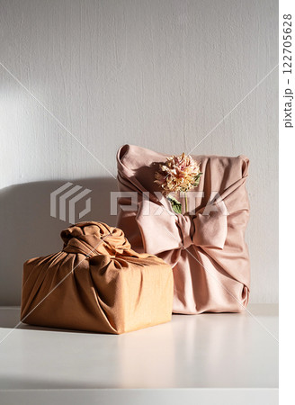 Elegant fabric wrapped gift boxes with dried flowers, styled on white table. Organic and perfect for zero waste holiday. Elegant fabric wrapped gift boxes with dried flowers, styled on white table. Organic and perfect for zero waste holiday. 122705628