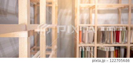 Modern wooden showcase rack with blurred fabric swatch materials hanging in the background 122705686