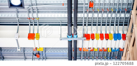 Electrical cable conduit with colorful junction box and part of plumbing pipeline on ceiling 122705688