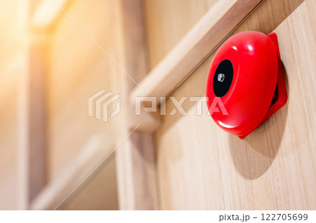 Red fire alarm bell mounted on wooden wall in office interior 122705699