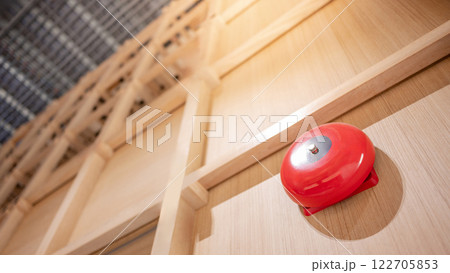 Red fire alarm bell mounted on wooden wall in office interior 122705853