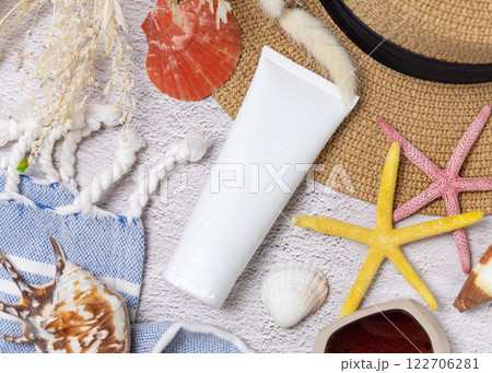 Sunscreen cream tube on hat near towel, seashells and starfishes top view, cosmetic mockup Sunscreen cream tube on hat near towel, seashells and starfishes top view, cosmetic mockup 122706281