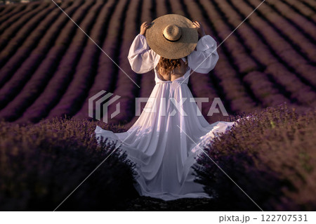 Here's a title following your specifications: Lavender Fields Woman Dress France: Sunset photoshoot, Provence, summer fashion elegance showcasing white dress amidst purple rows. 122707531