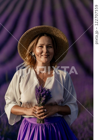 A woman wearing a straw hat and holding a bunch of lavender flowers A woman wearing a straw hat and holding a bunch of lavender flowers 122707559