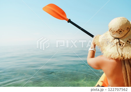 Woman in kayak back view. Happy woman with long hair in a swimsuit and hat floating in kayak on the sea. Summer holiday vacation. Summer holidays vacation at sea. Woman in kayak back view. Happy woman with long hair in a swimsuit and hat floating in kayak on the sea. Summer holiday vacation. Summer holidays vacation at sea. 122707562