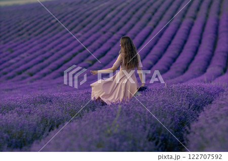 A woman is walking through a field of purple flowers 122707592