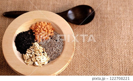Rustic wooden spoon and bowl containing seeds, oats, and lentils arranged on natural woven surface. Eco-friendly presentation perfect for promoting sustainability and healthy eating habit Natural wood Rustic wooden spoon and bowl containing seeds, oats, and lentils arranged on natural woven surface. Eco-friendly presentation perfect for promoting sustainability and healthy eating habit Natural wood 122708221