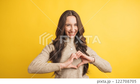 Smiling woman forming heart shape with hands 122708705