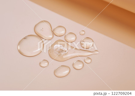 Few drops of serum on a beige background. Few drops of serum on a beige background. 122709204