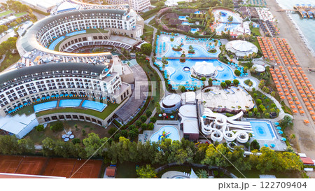 Aerial view of a beachfront luxury resort with modern architecture, pools, and a water park Aerial view of a beachfront luxury resort with modern architecture, pools, and a water park 122709404