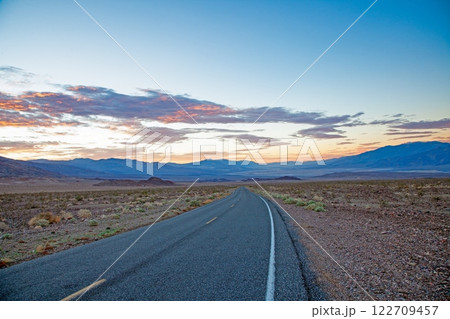 Scenic desert road at sunset with colorful clouds and mountain backdrop 122709457