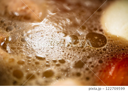 Hot broth simmering with bubbles and fat droplets creating an interesting texture on the surface, ideal for culinary or food science contexts 122709599