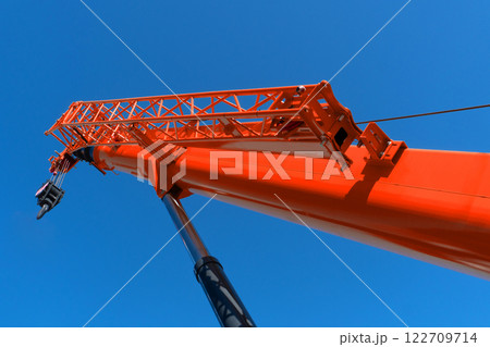 Construction crane arm with hook against blue sky background. Mobile construction tower crane with telescopic boom Construction crane arm with hook against blue sky background. Mobile construction tower crane with telescopic boom 122709714