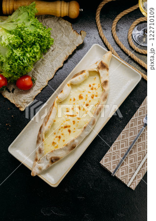 Turkish cheese pide with melted mozzarella on a plate in elegant and traditional food presentation Turkish cheese pide with melted mozzarella on a plate in elegant and traditional food presentation 122710109