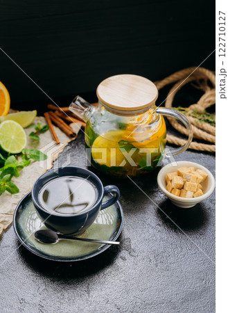Herbal citrus tea with fresh mint, lime, orange and brown sugar served in a glass teapot and cup 122710127