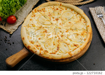 Gourmet pear and blue cheese pizza with pine nuts on wooden board in stylish restaurant setting 122710162