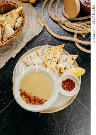 Creamy lentil soup with flatbread, sesame seeds, chili flakes, and lemon, served in an elegant style Creamy lentil soup with flatbread, sesame seeds, chili flakes, and lemon, served in an elegant style 122710165