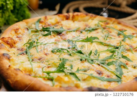 Gourmet four-cheese pizza with arugula, served on a wooden board in a stylish restaurant setting Gourmet four-cheese pizza with arugula, served on a wooden board in a stylish restaurant setting 122710176