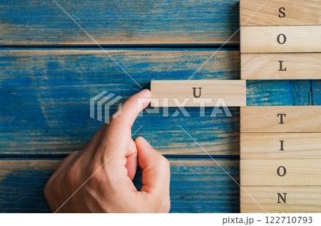 Male hand pushing a wooden peg into a stack of them to spell the word Solution Male hand pushing a wooden peg into a stack of them to spell the word Solution 122710793
