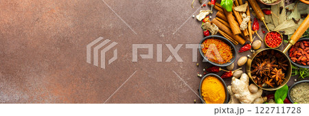 A visually striking arrangement of fresh spices and herbs on a brown surface, highlighting their vivid colors, intricate details, and rich culinary essence, banner 122711728
