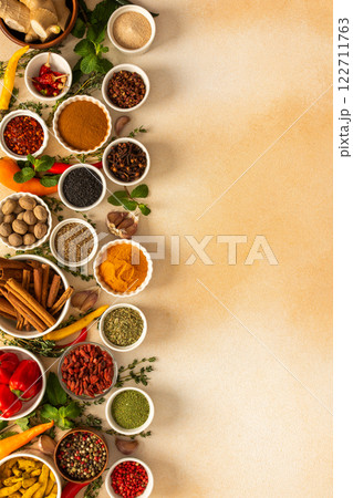 Spread of spices and herbs on a beige surface, featuring essential cooking ingredients for flavorful, home-cooked recipes, top view and copy space 122711763
