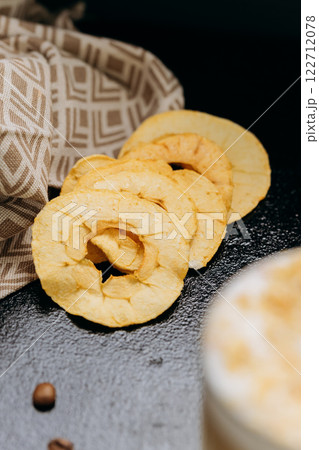 Crispy dried apple rings on dark textured background, perfect for healthy snacking and food styling Crispy dried apple rings on dark textured background, perfect for healthy snacking and food styling 122712078