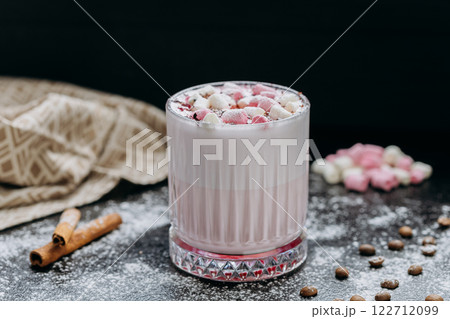 Cup of pink hot chocolate with marshmallows and powdered sugar on a rustic dark background 122712099