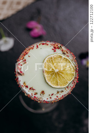 Elegant citrus cocktail in tall glass with floral garnish and dried lime slice, perfect for summer 122712100