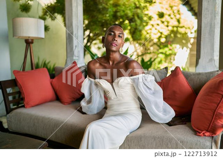 Person in white dress on villa couch. LGBTQ marriage concept. Tropical, luxury vibe. Inclusive wedding venue, welcoming atmosphere. Fashion, elegance, bridal event. Diverse representation. Person in white dress on villa couch. LGBTQ marriage concept. Tropical, luxury vibe. Inclusive wedding venue, welcoming atmosphere. Fashion, elegance, bridal event. Diverse representation. 122713912