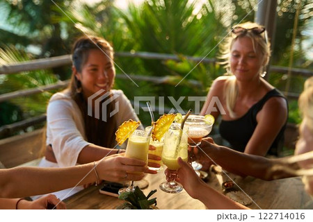 Diverse group of women at tropical restaurant toast with cocktails. Celebration. Vacation mood. Fun bachelorette party on travel. Laughter in paradise. Enjoying sun vibes together. Happy moments. Diverse group of women at tropical restaurant toast with cocktails. Celebration. Vacation mood. Fun bachelorette party on travel. Laughter in paradise. Enjoying sun vibes together. Happy moments. 122714016