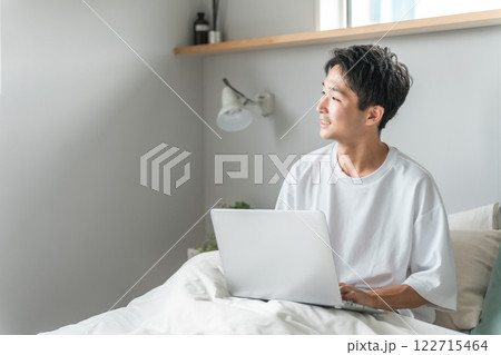 在宅勤務・テレワーク・リモートワーク・在宅ワークで朝ベッドルームでパソコンを使う男性 在宅勤務・テレワーク・リモートワーク・在宅ワークで朝ベッドルームでパソコンを使う男性 122715464