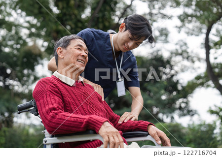 Healthcare professional providing joyful care to senior man in wheelchair, highlighting trust and comfort 122716704